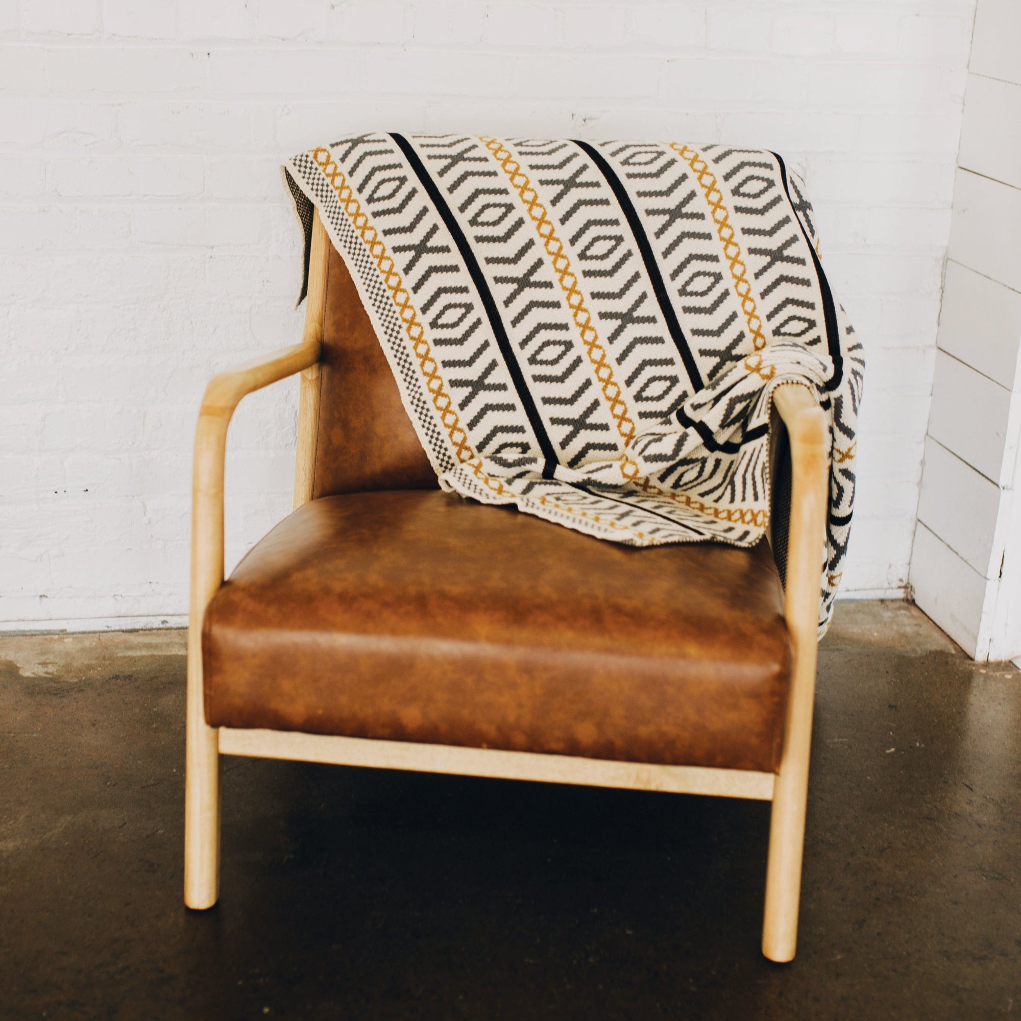 Seek & Swoon Otok Throw draped over the back of a leather chair.