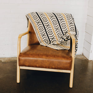Seek & Swoon Otok Throw draped over the back of a leather chair.